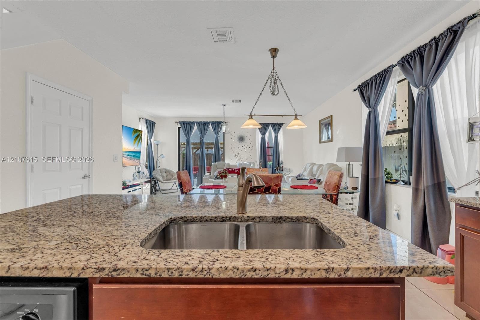 Kitchen island featuring stone countertops, an undermount double-basin stainless steel sink, and a gooseneck faucet