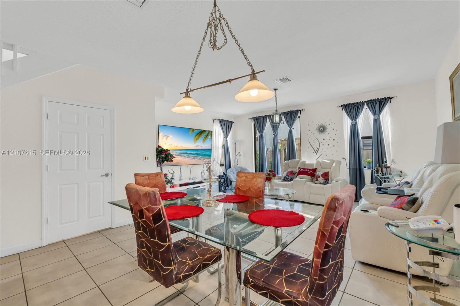 Neutral-toned ceramic tile flooring, dual-light metal pendant fixture, and multiple windows with drapery hardware