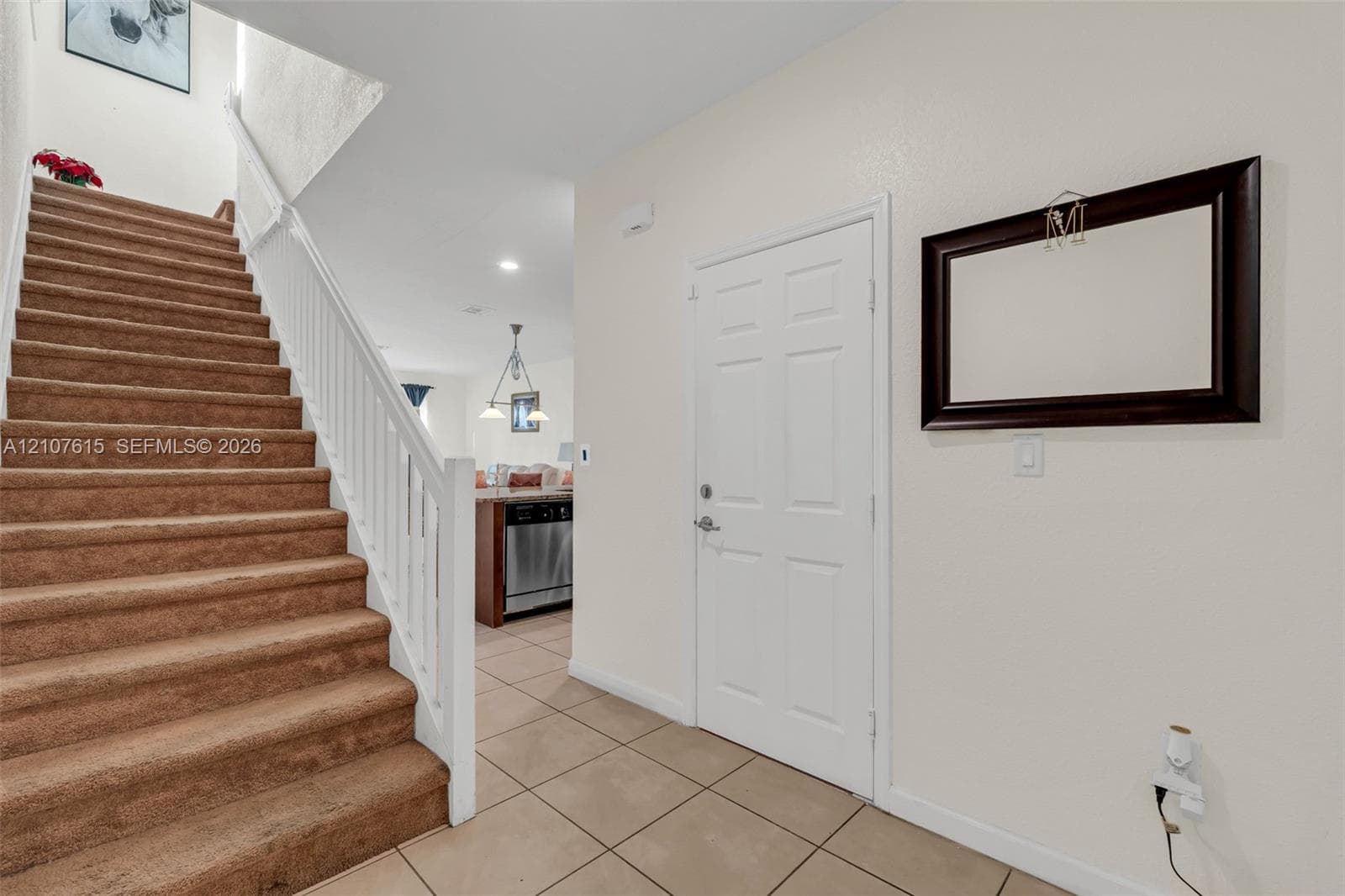 Entryway featuring neutral tile flooring, a staircase with white balusters and carpeted treads, and a multi-panel door