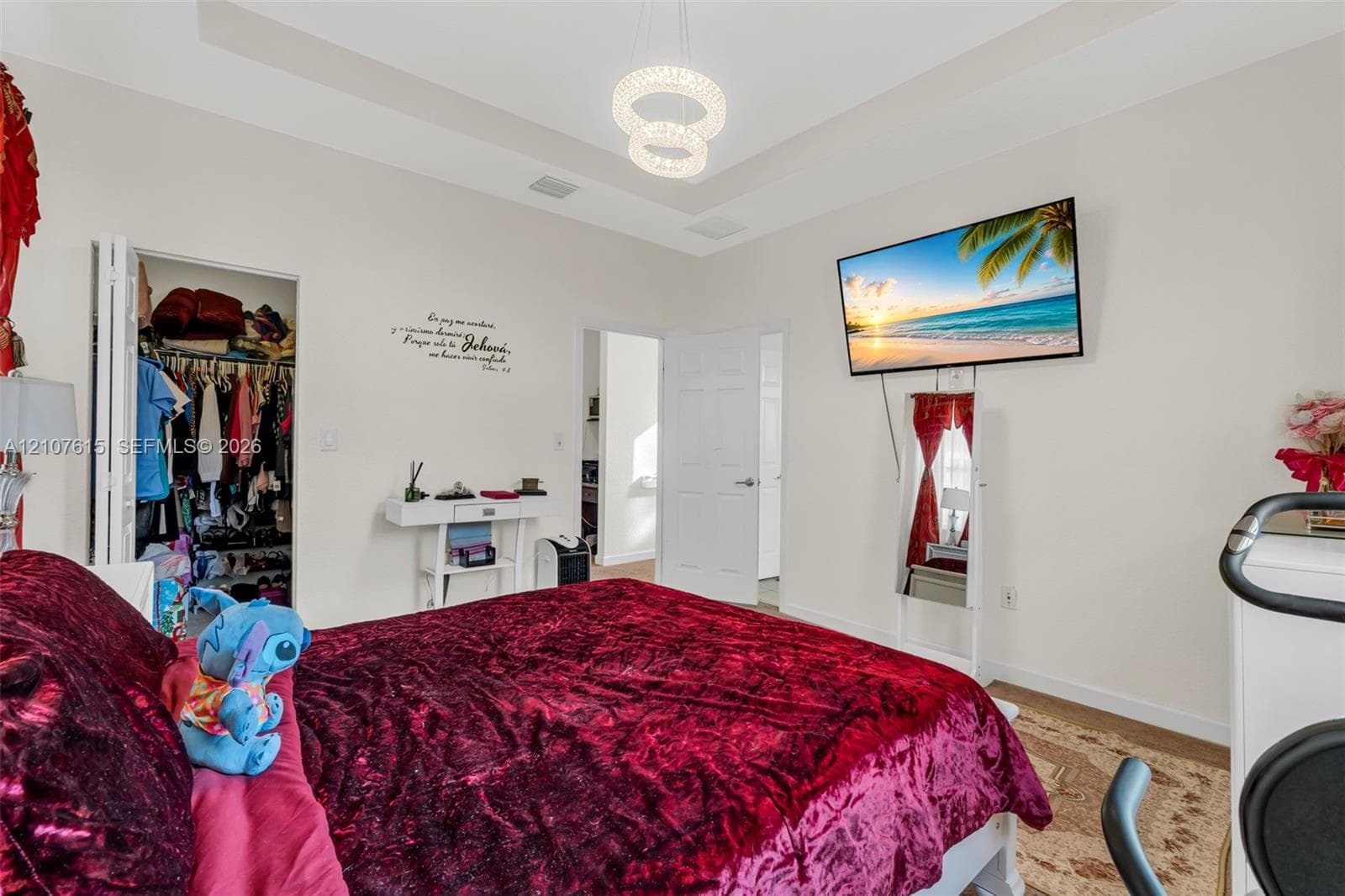 Tray ceiling with a decorative dual-ring pendant light fixture, bi-fold closet doors, and a six-panel interior door