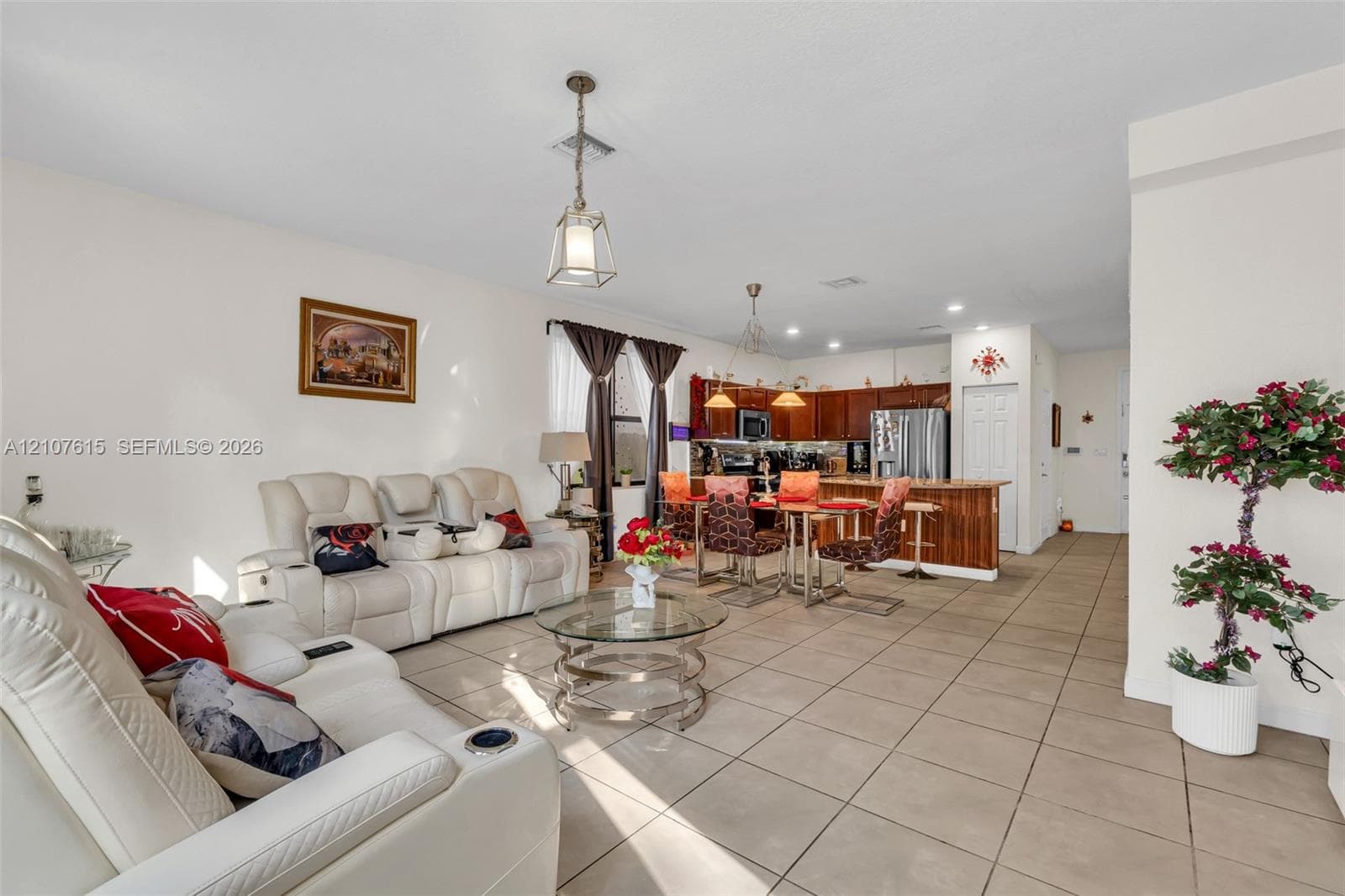 Large-format tile flooring, kitchen featuring wood cabinetry and a breakfast bar, and pendant lighting fixtures