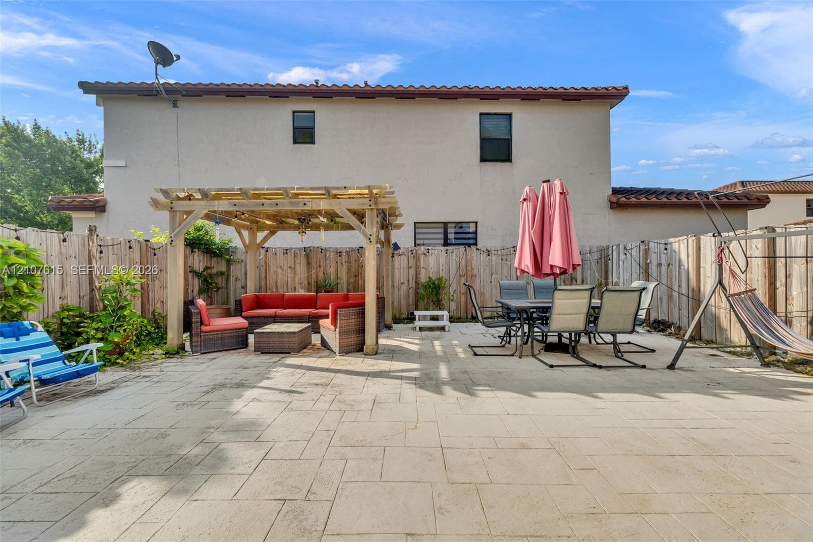 Rear patio featuring stamped concrete paving, a wooden pergola, and perimeter wood fencing