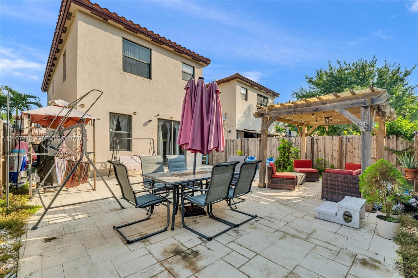Stucco exterior featuring a tiled roof and a paved patio area with a wooden pergola