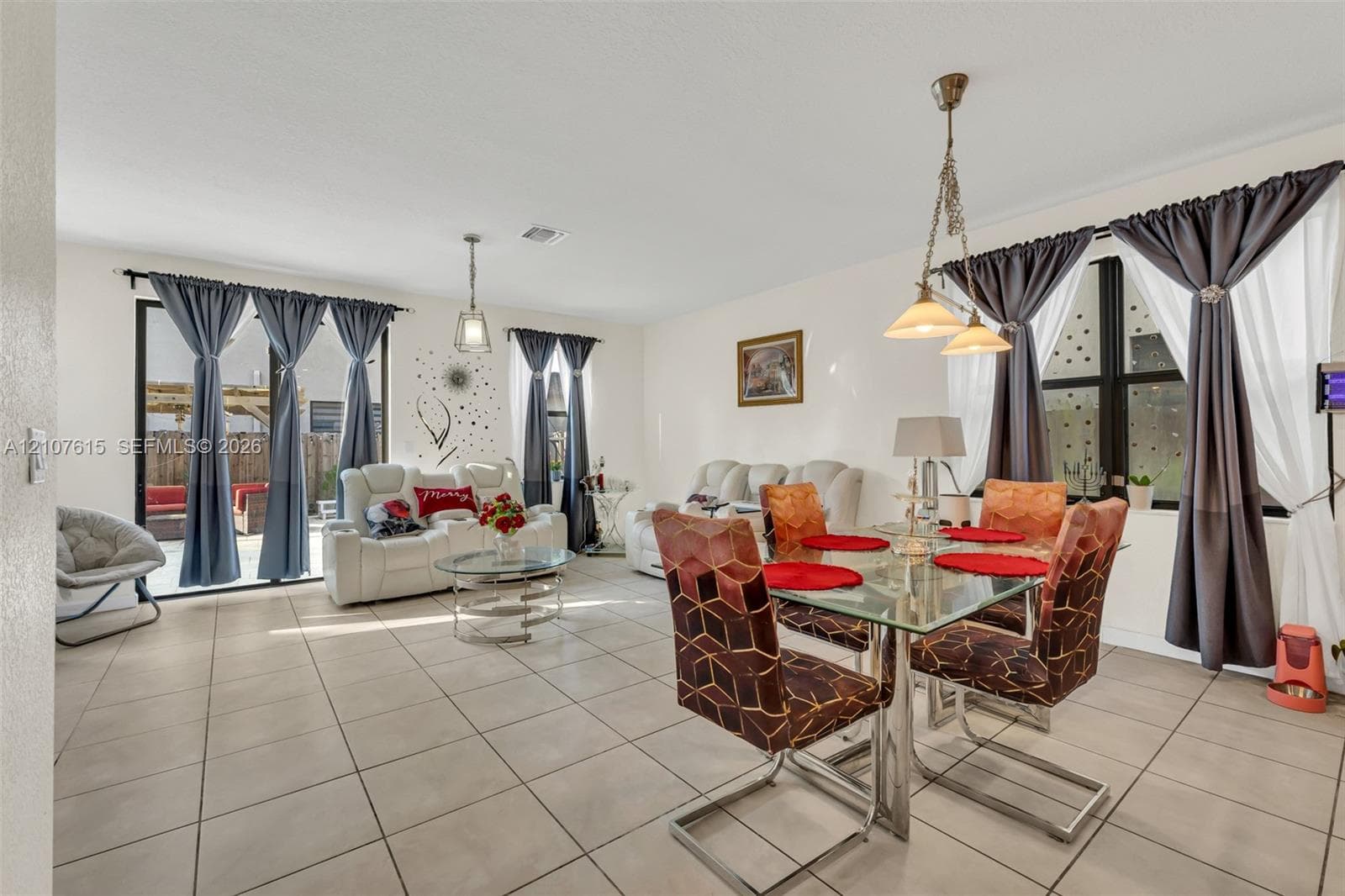 Open-concept area featuring light-toned tile flooring, oversized glass sliding doors, and dual pendant light fixtures