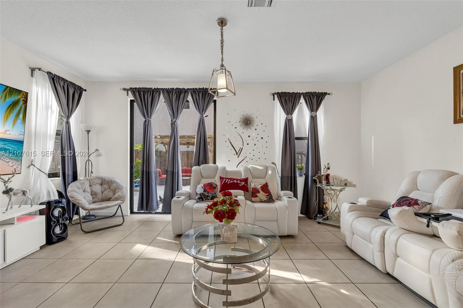 Living area featuring neutral tile flooring, recessed ceiling lighting, a contemporary metal pendant fixture, and sliding glass doors