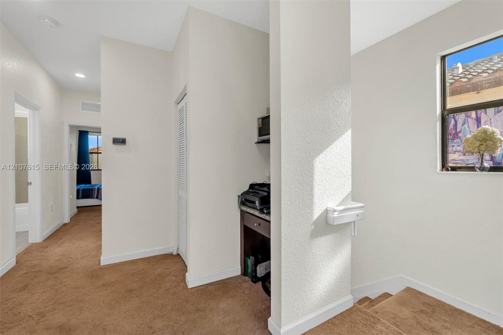 Built-in desk area with stone-surface countertop, carpeted flooring, neutral wall finishes, and louvered-door closet