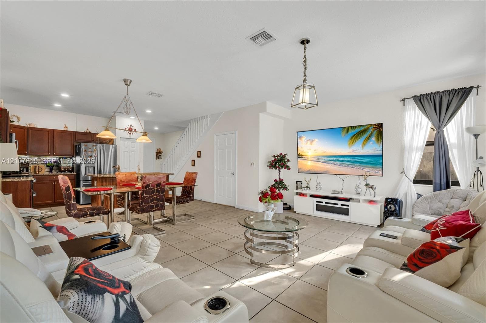 Open-concept interior featuring large-format neutral tile flooring, recessed lighting, and wooden cabinetry in the kitchen area