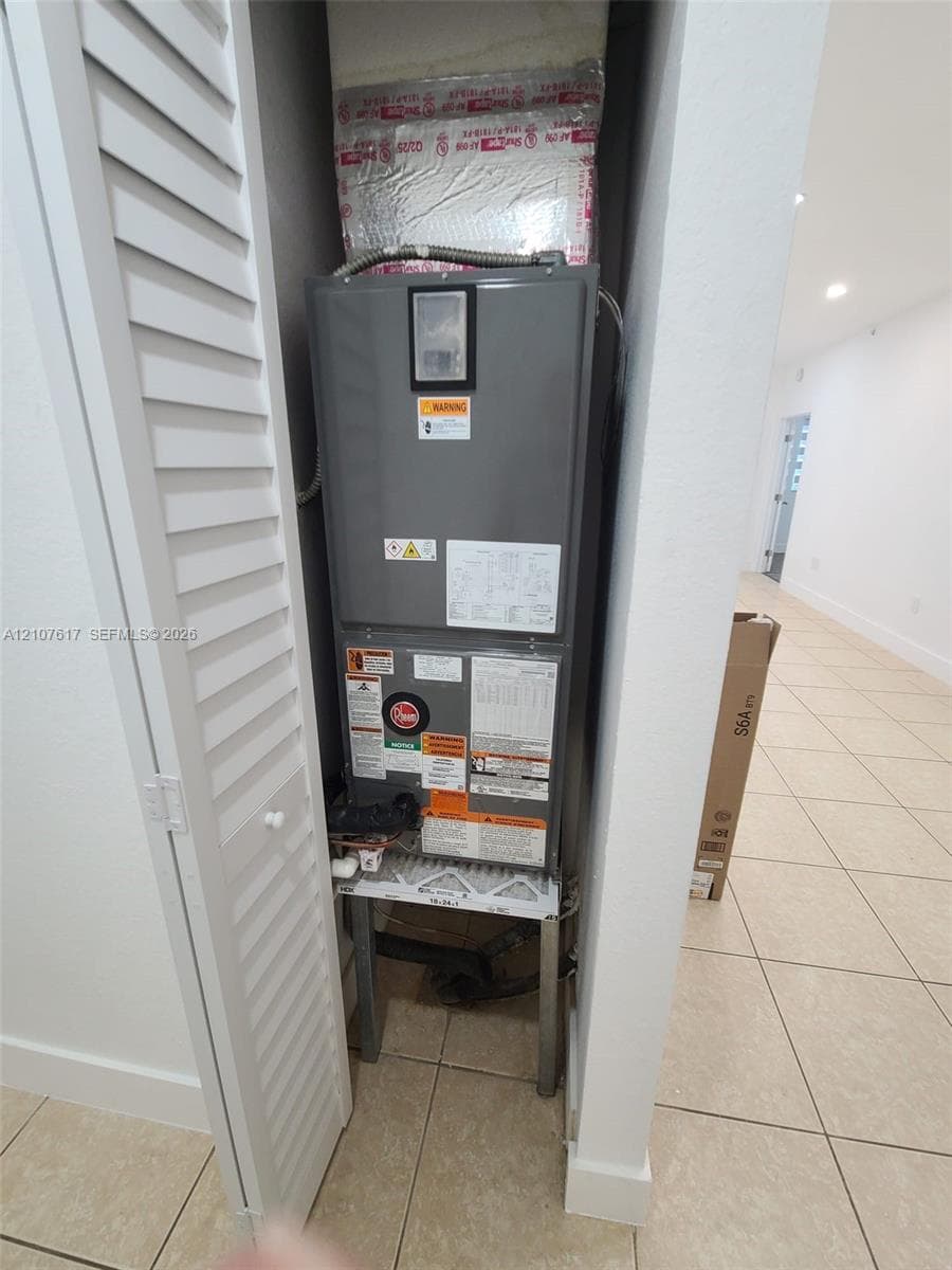 Utility closet featuring a central HVAC air handler unit enclosed by louvered bi-fold doors