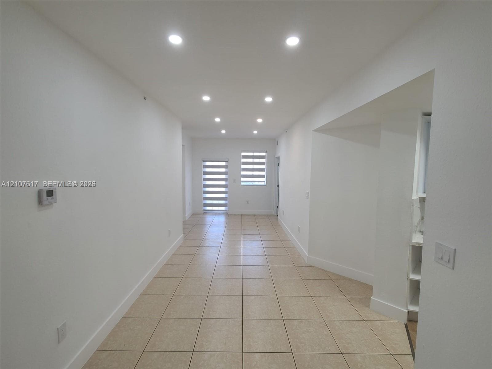 Interior space featuring neutral tile flooring, recessed lighting, and tiered roller window shades