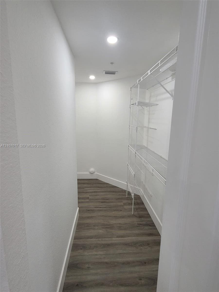 Walk-in storage space featuring wood-finish flooring and integrated white wire shelving