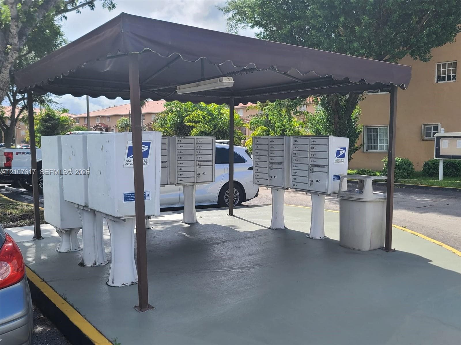 Covered community mail station featuring central clustered mailbox units on a concrete pad