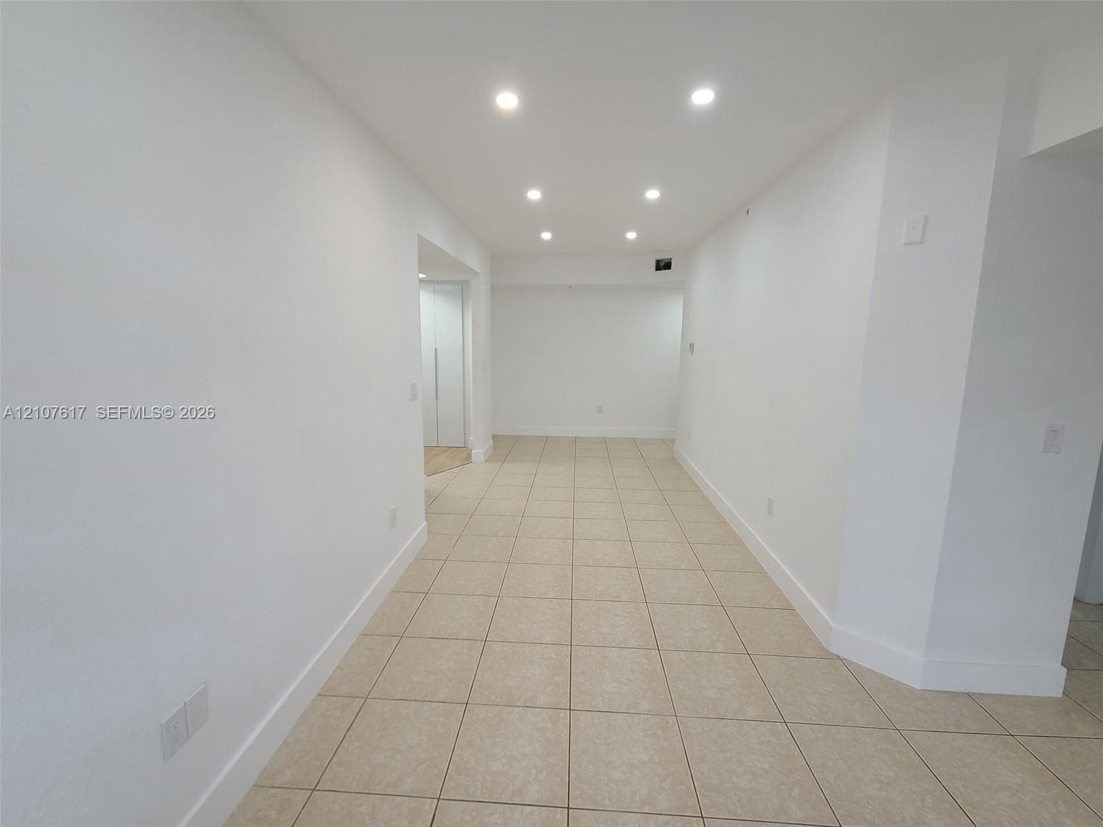 Interior space featuring neutral tile flooring, recessed ceiling lighting, and crisp white wall finishes