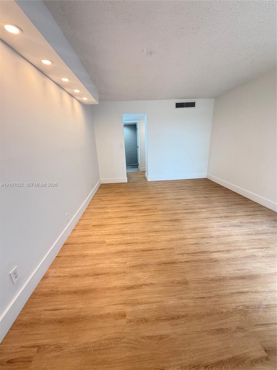 Interior space featuring wood-finish flooring, recessed lighting within a soffit, and smooth wall finishes