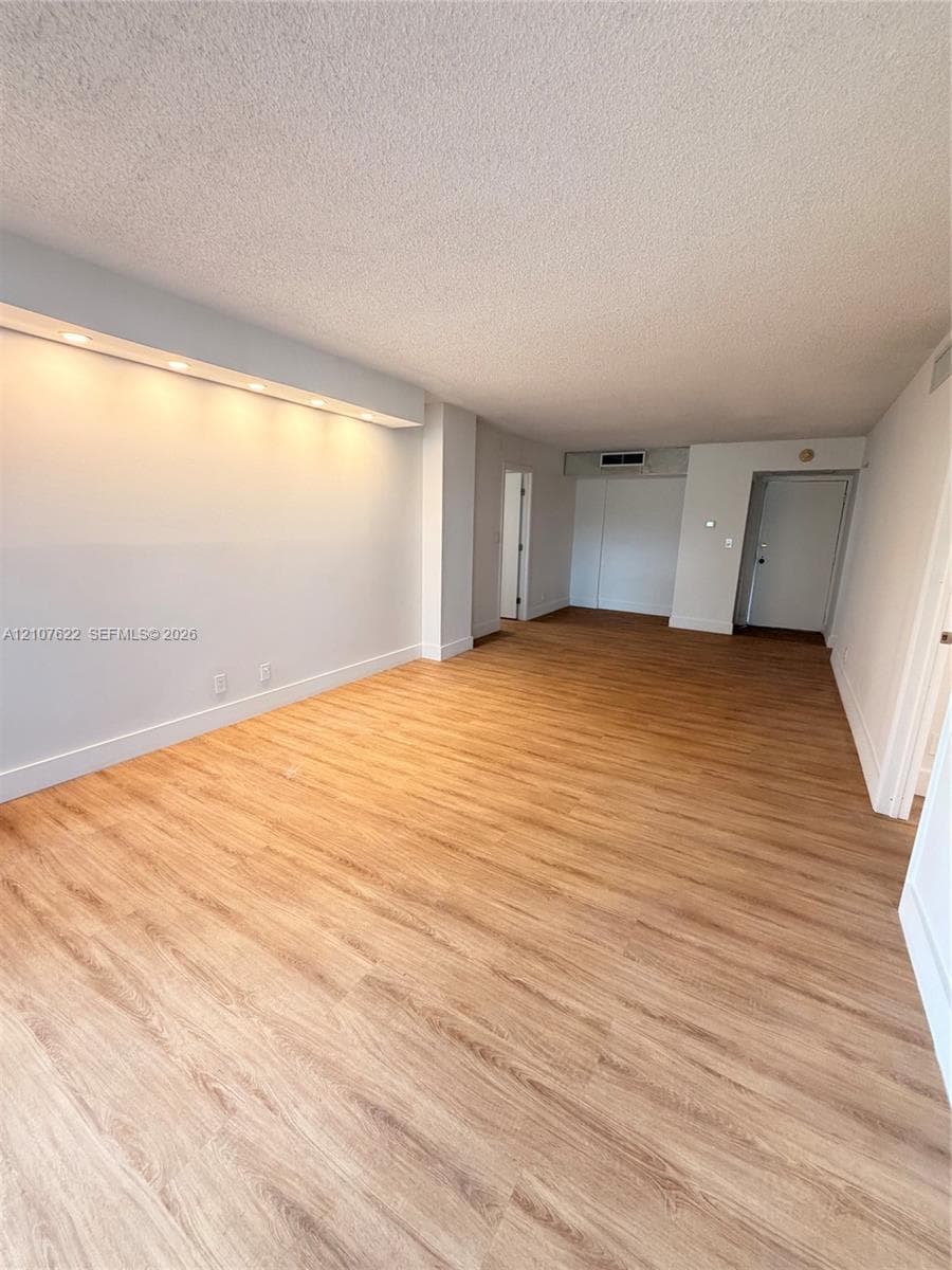 Open floor plan featuring wood-finish flooring, recessed soffit lighting, and neutral wall tones