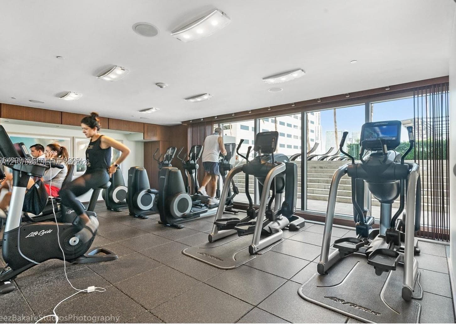 Fitness center featuring rubberized flooring, recessed lighting, wood-finish wall paneling, and floor-to-ceiling glass windows
