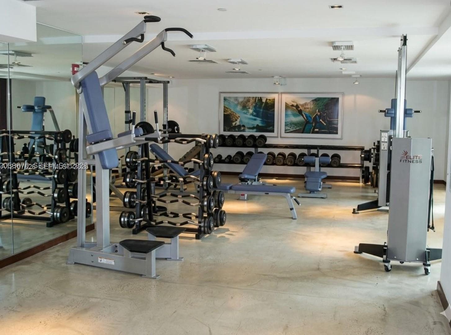 Fitness room featuring polished concrete flooring, full-length wall-mounted mirrors, and recessed ceiling lighting
