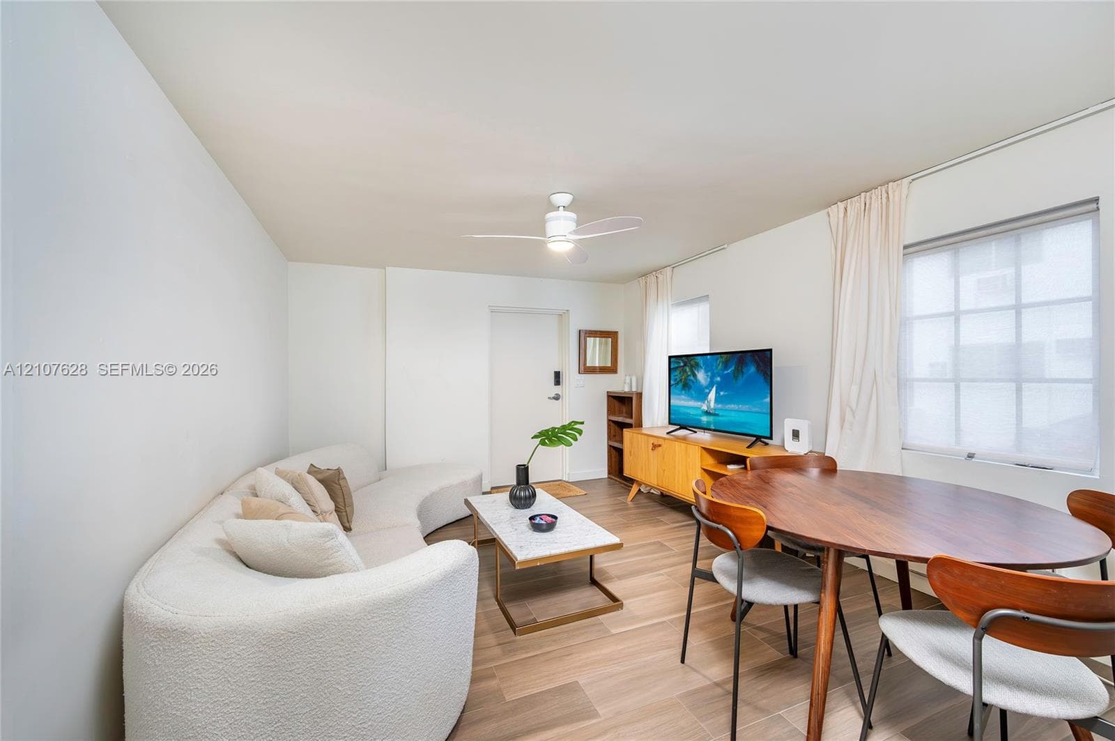 Living area featuring wood-finish flooring, a ceiling fan, and multi-pane windows