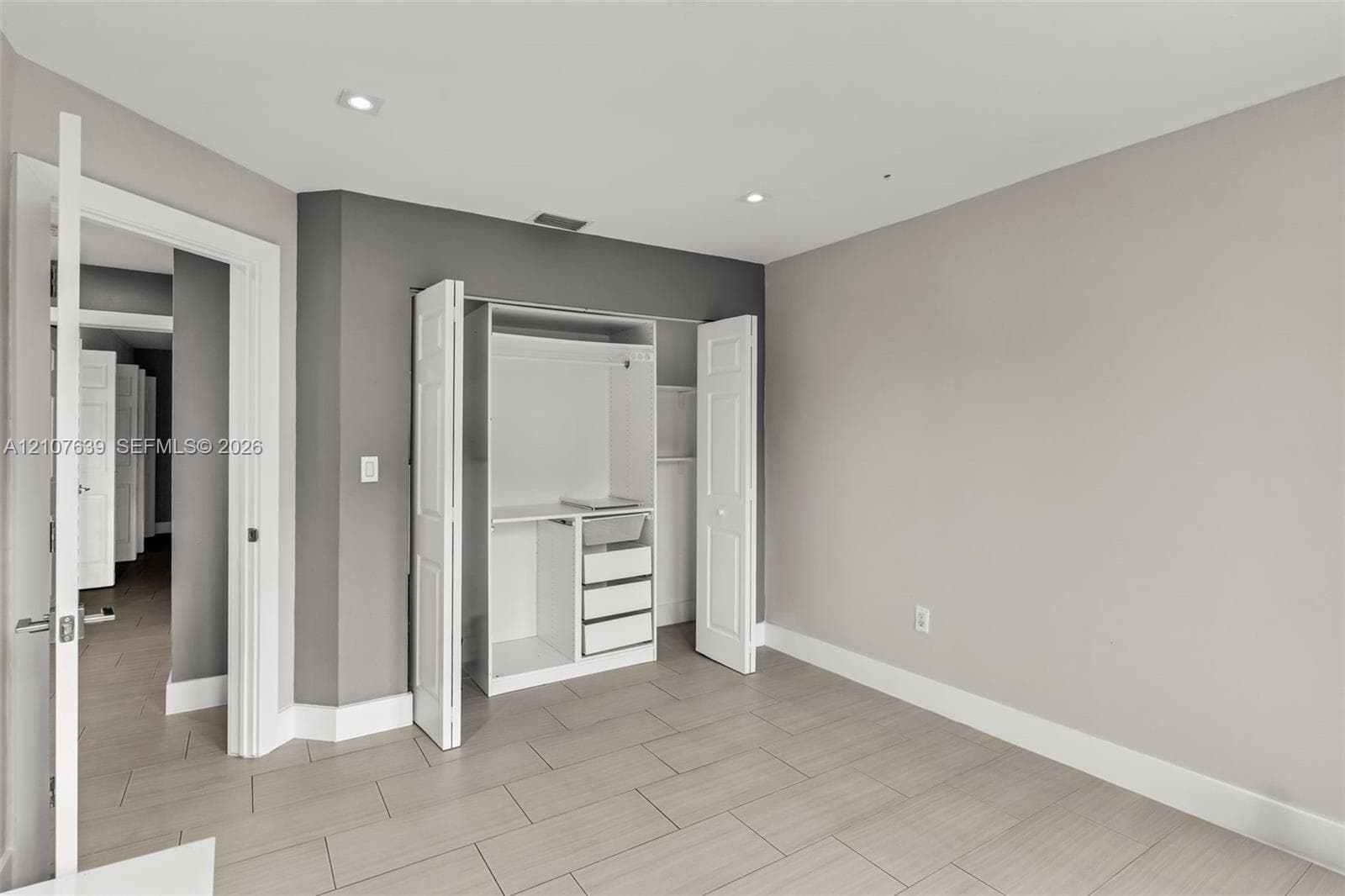 Room featuring large-format tile flooring, recessed lighting, and a built-in closet system with integrated shelving and drawers
