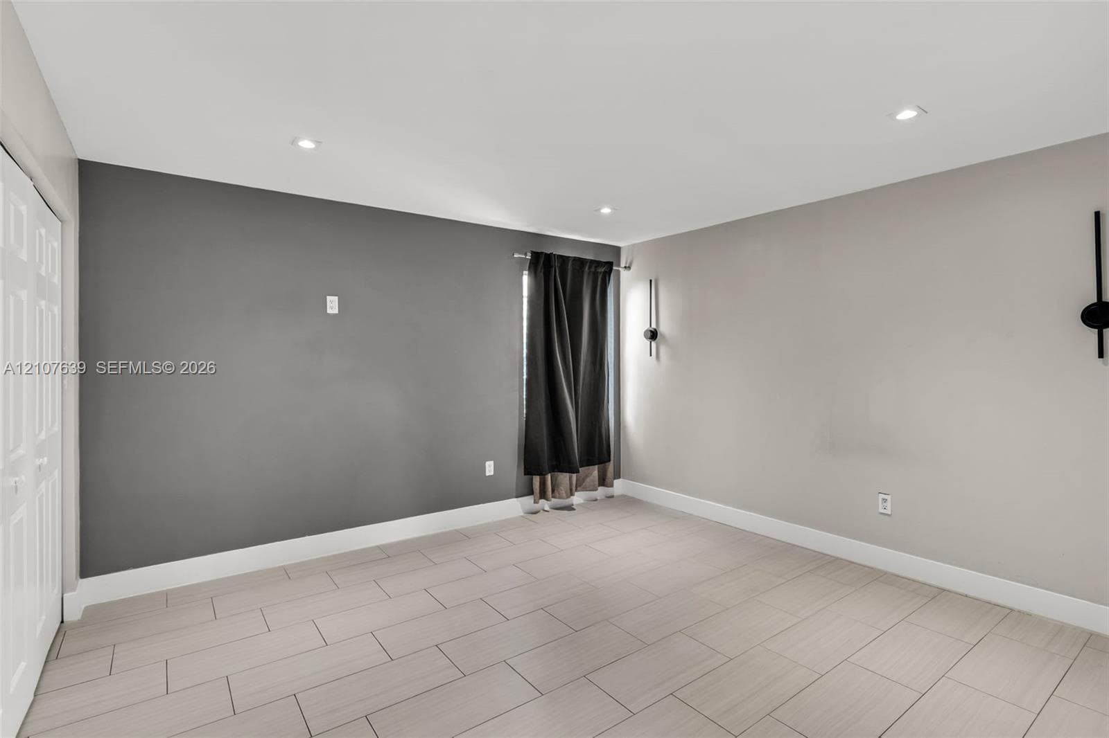 Interior space featuring neutral wall tones, large-format tile flooring, recessed ceiling lighting, and dual wall-mounted light fixtures