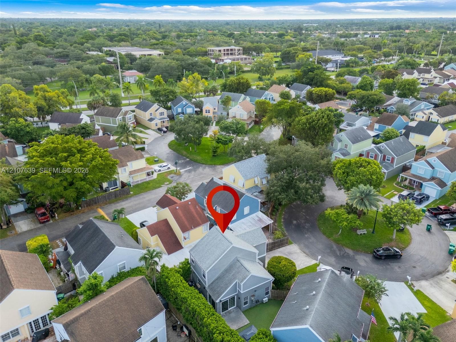 Aerial perspective of a multi-story residence featuring a shingled roof, paved driveway, and private backyard area