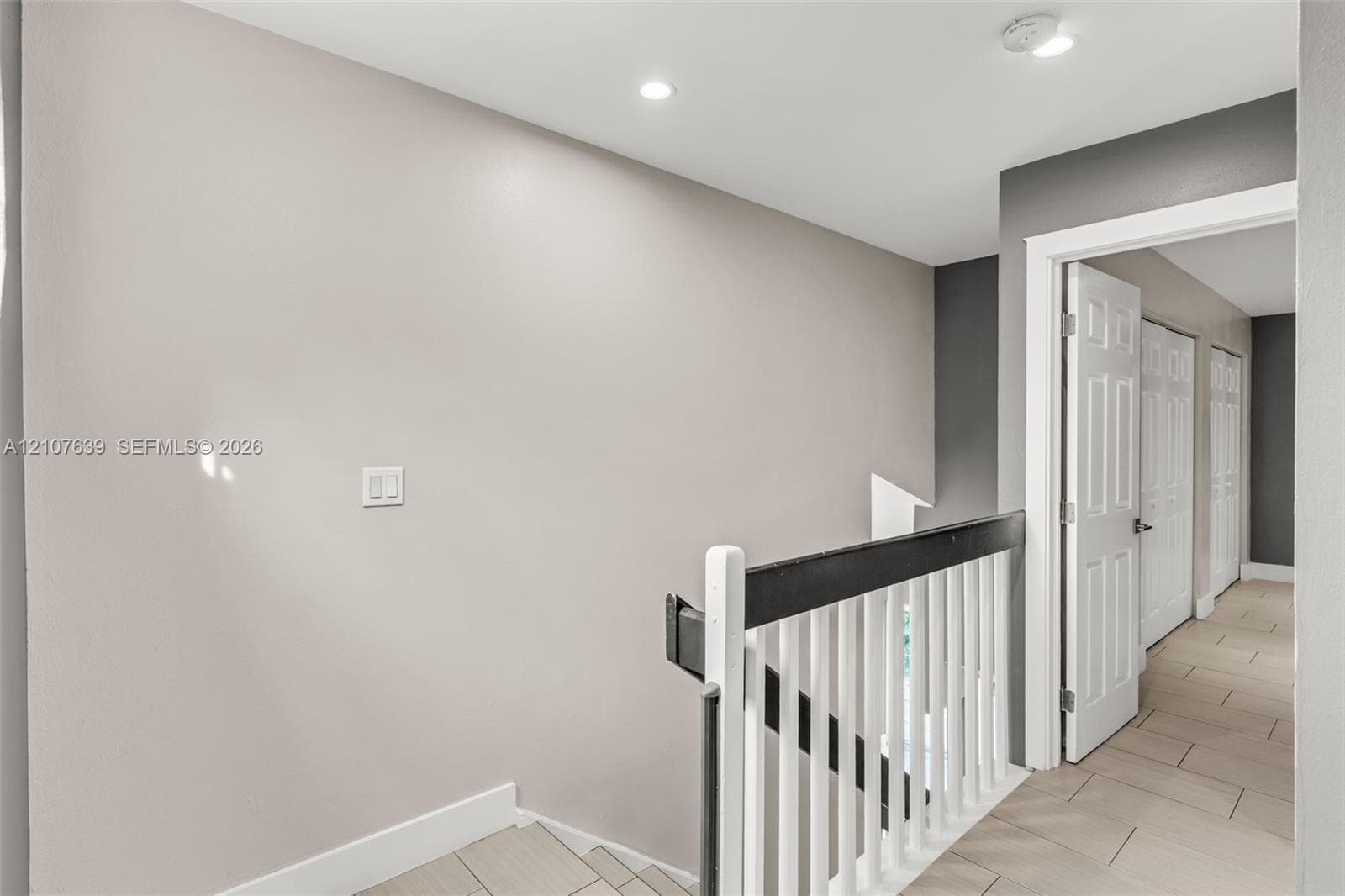 Staircase featuring a high-contrast railing with white balusters and a dark handrail, neutral wall tones, recessed lighting, and tile flooring