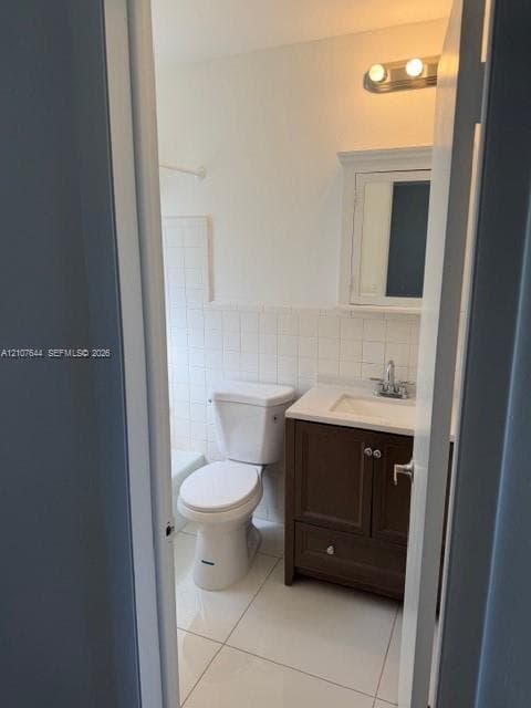 Bathroom featuring a dark wood-finish vanity, light-toned countertop, inset medicine cabinet, tile flooring, and tile-surround tub