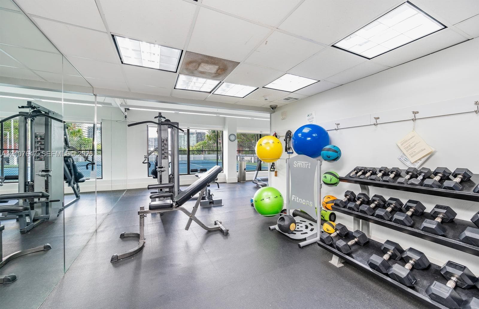 Fitness area featuring large-scale wall mirrors, recessed drop-ceiling lighting, and heavy-duty rubber flooring
