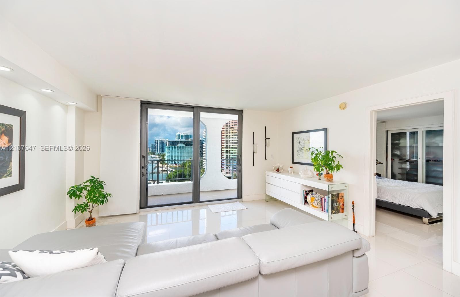 Open-concept living space featuring high-gloss tile flooring, recessed ceiling lighting, and large sliding glass doors providing outdoor access