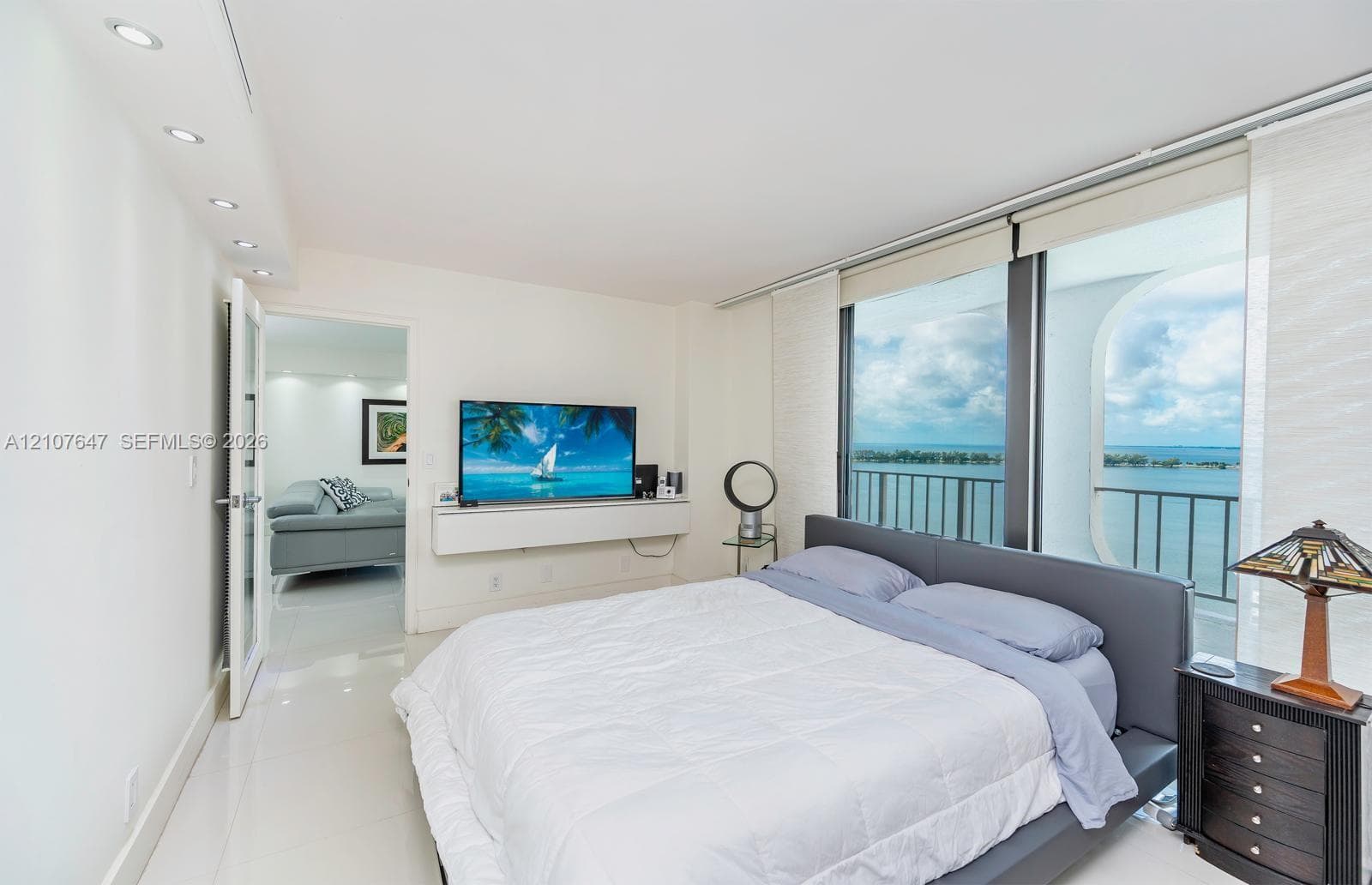 Floor-to-ceiling windows with balcony access, recessed ceiling lighting, light-colored polished flooring, and wall-mounted floating cabinetry