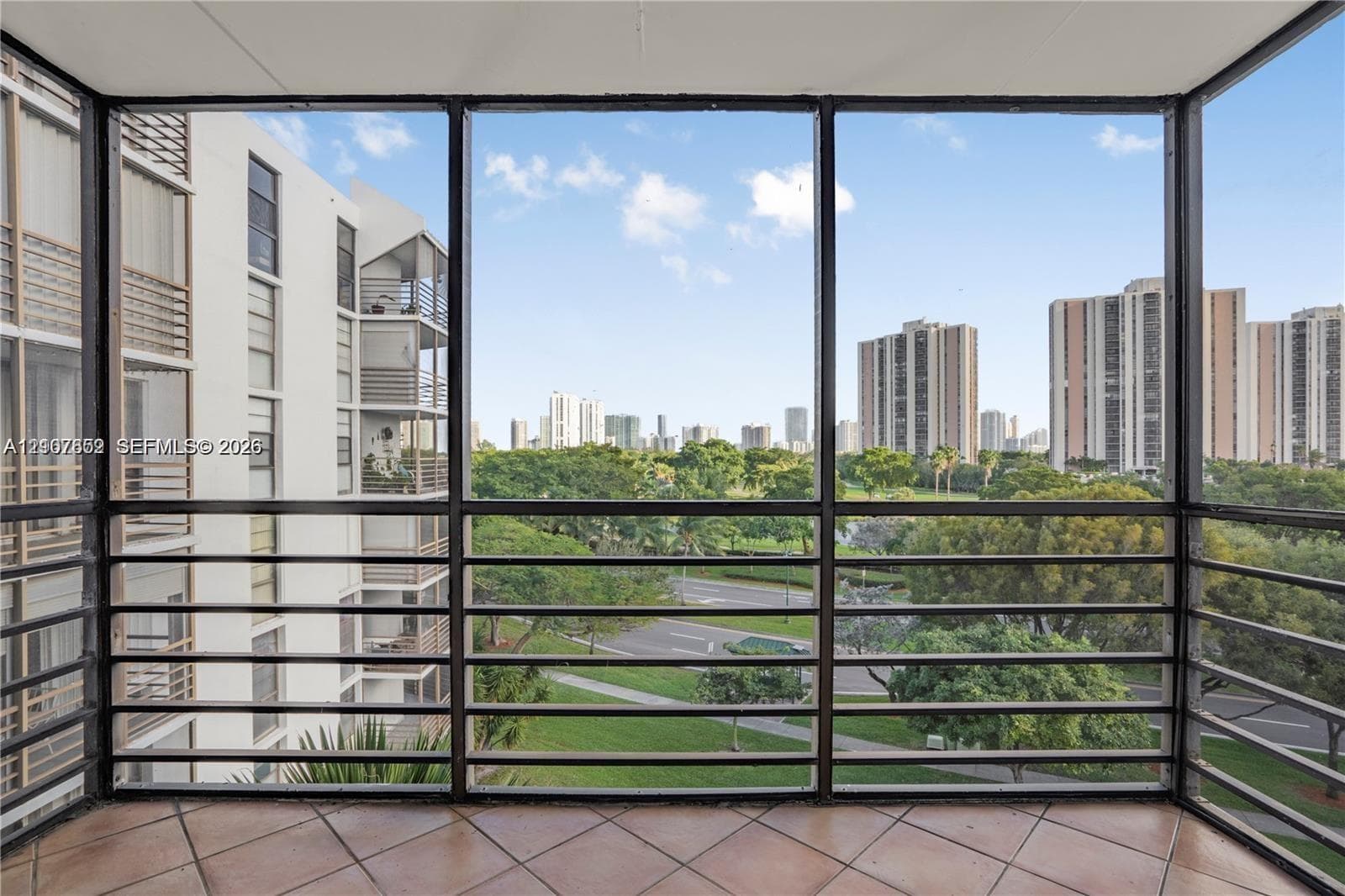 Enclosed balcony featuring tile flooring and metal screen framing