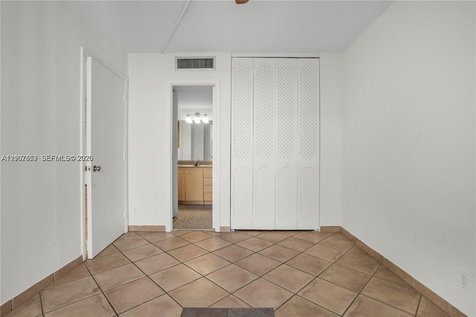 Interior space featuring neutral wall-to-wall tile flooring, white bi-fold closet doors, and a solid-core interior door