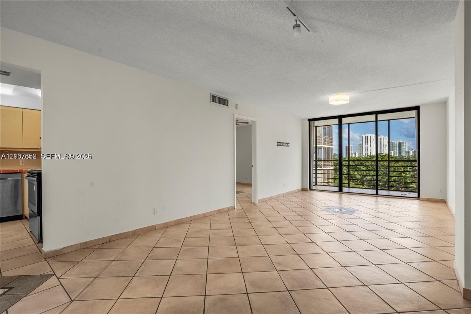 Open living area featuring neutral ceramic tile flooring, floor-to-ceiling sliding glass doors, and recessed ceiling lighting