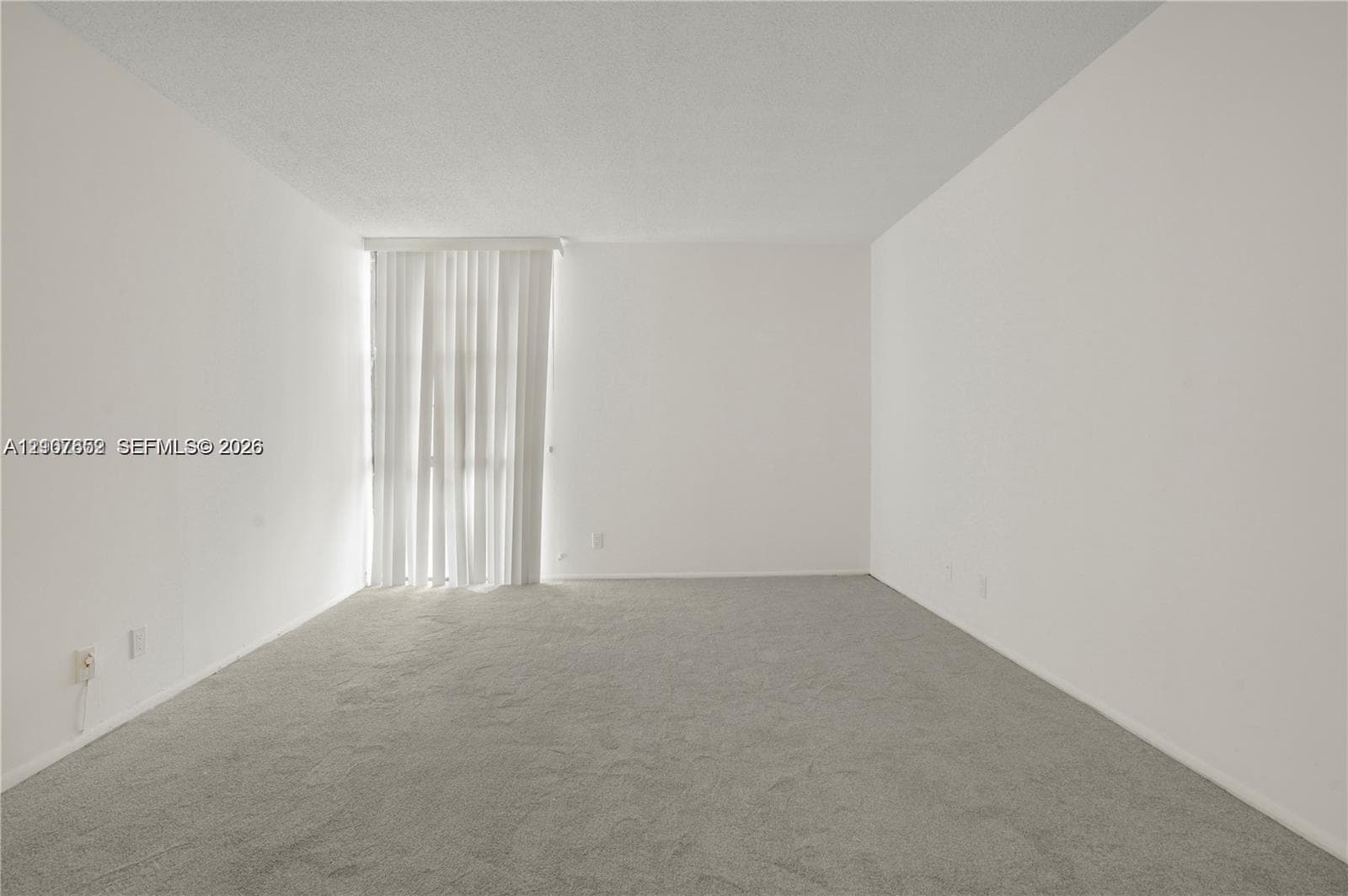 Neutral-toned interior space featuring wall-to-wall carpeting and floor-to-ceiling vertical blinds