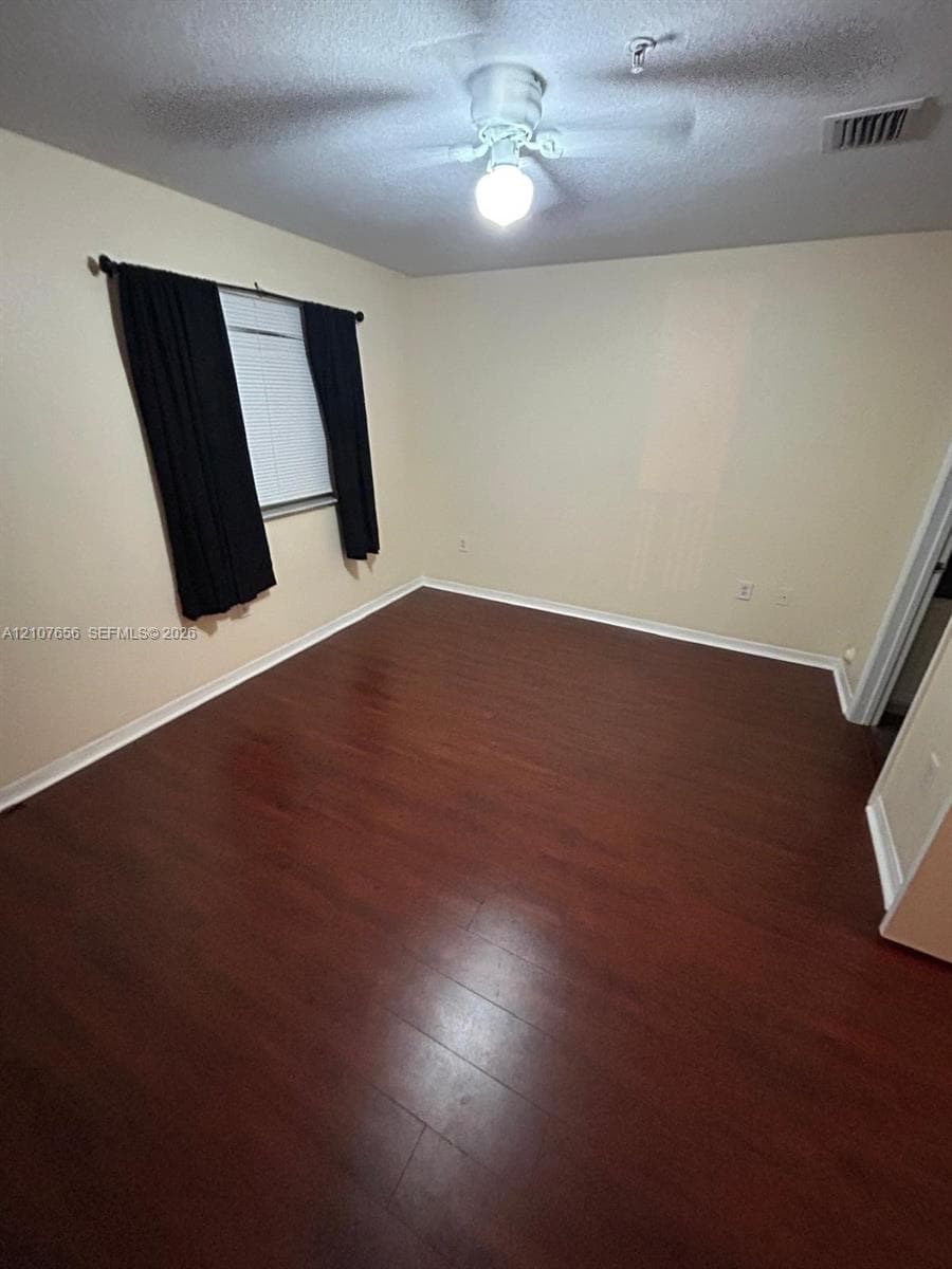 Room featuring wood-finish flooring, a ceiling fan with integrated lighting, and a single-pane window with horizontal blinds
