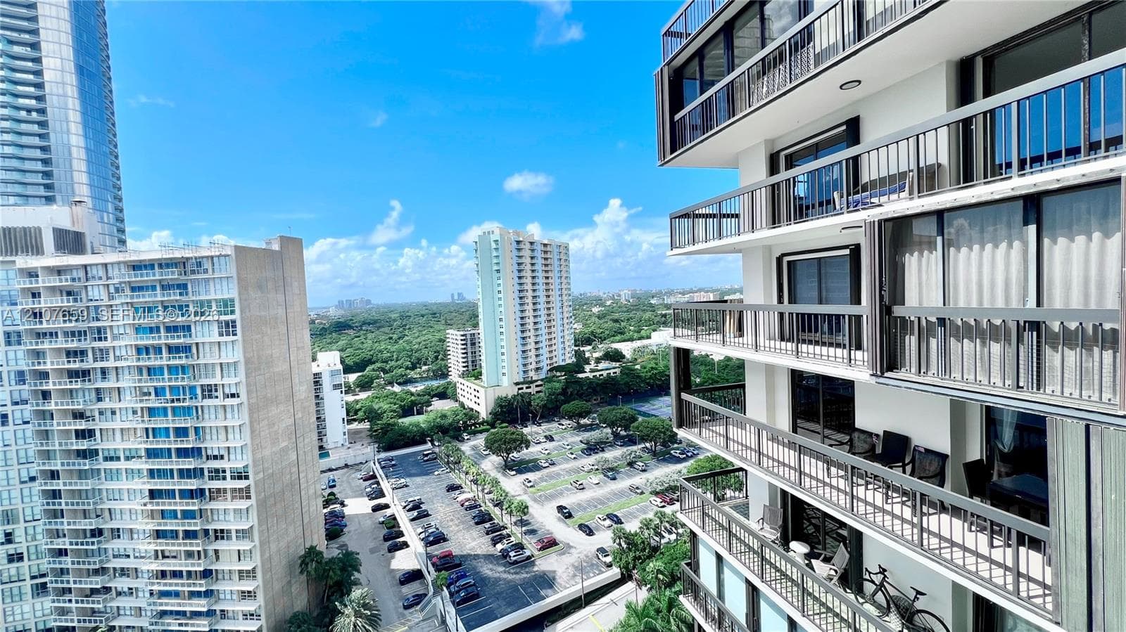High-rise exterior featuring stacked cantilevered balconies with dark metal railings, floor-to-ceiling glass sliding doors, and horizontal architectural framing