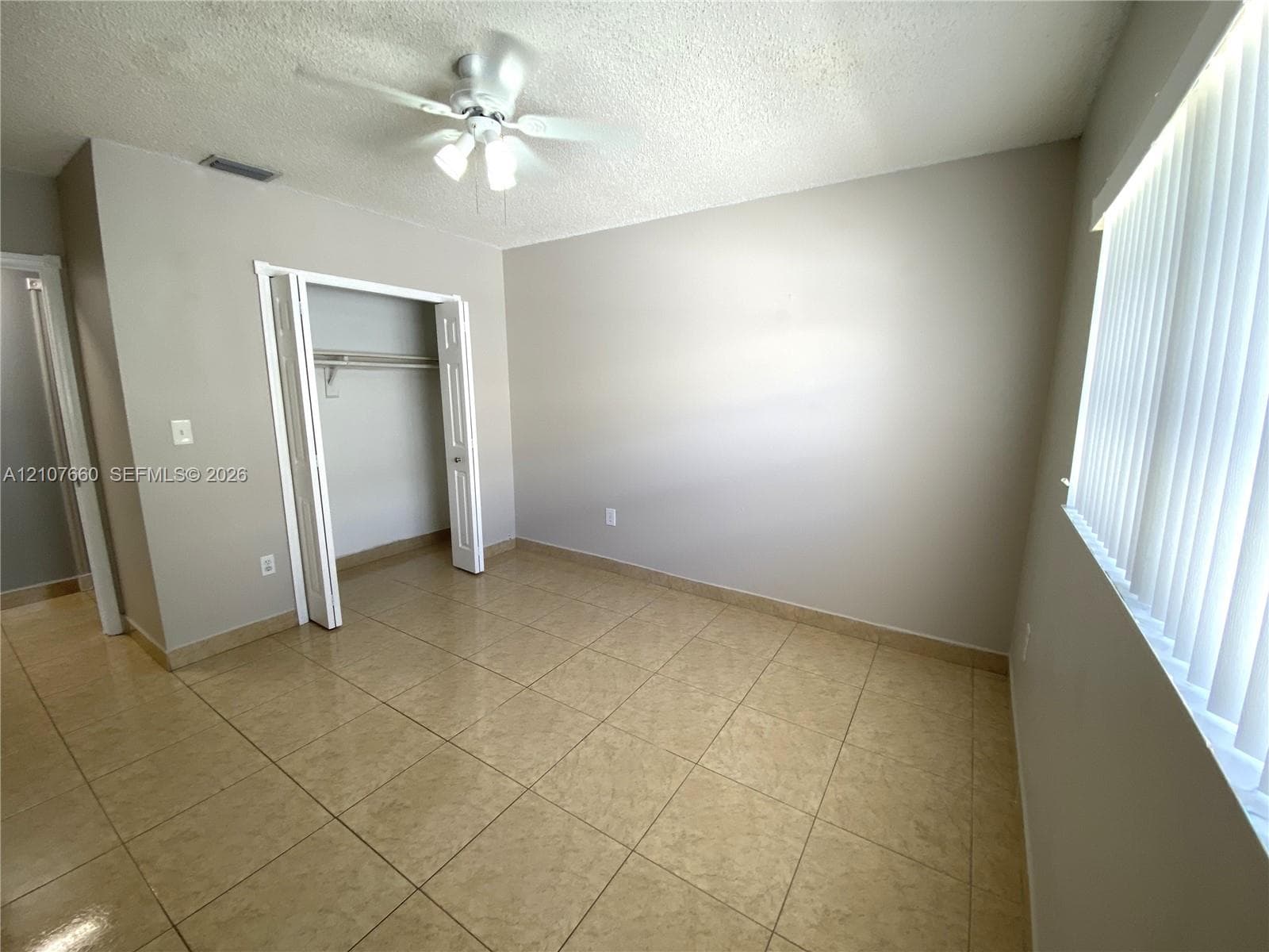 2nd Bedroom - Neutral-toned interior featuring large-format ceramic tile flooring, a ceiling fan with multi-light fixture, and built-in closet with double-panel doors