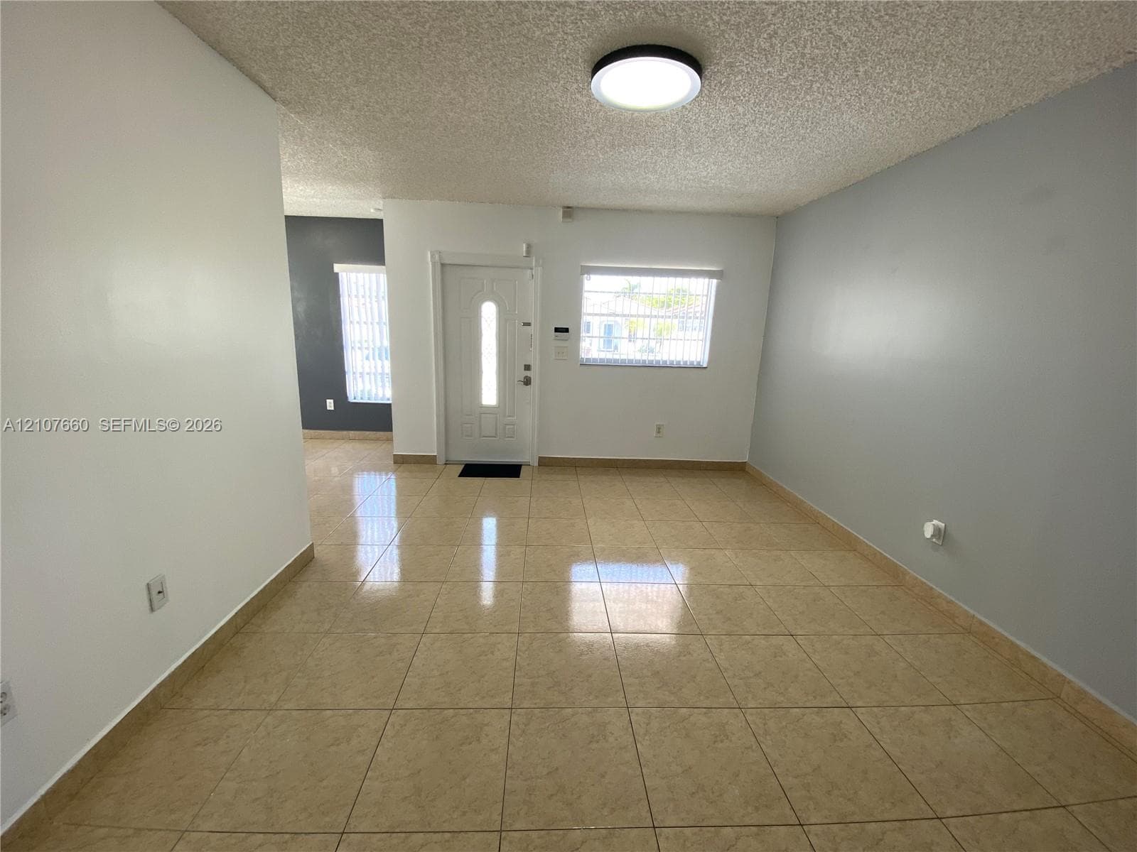 Tile flooring, neutral wall tones, multi-panel entry door with glass insert, and flush-mount ceiling lighting