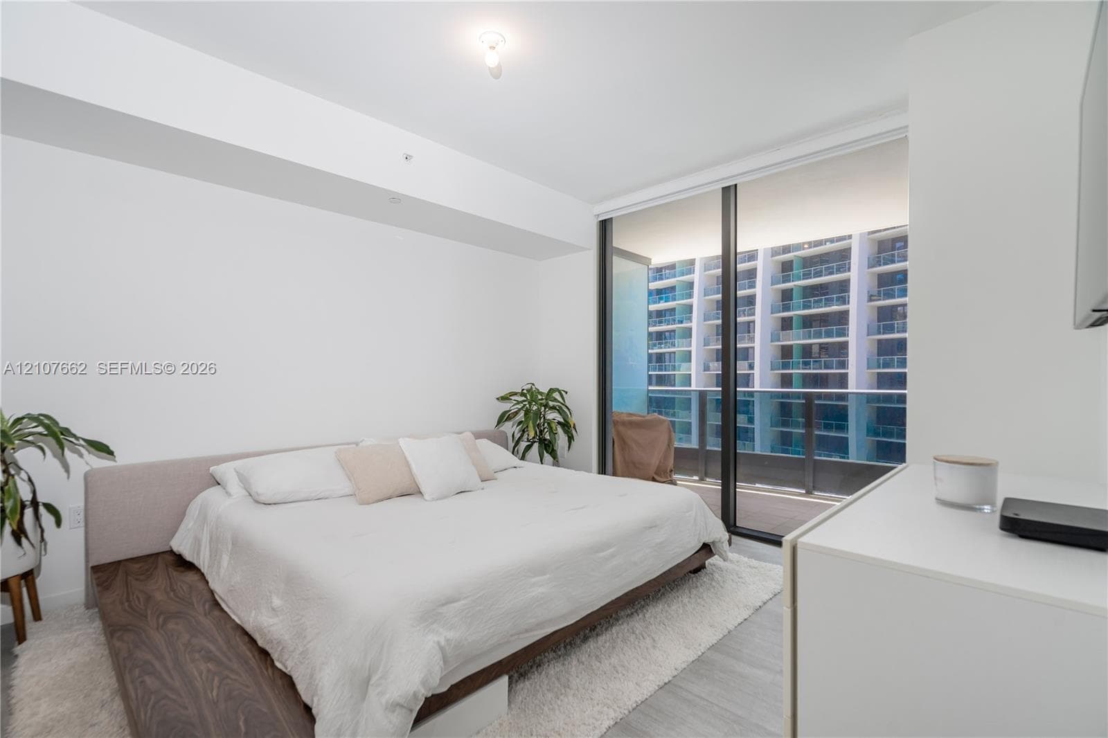 Floor-to-ceiling glass sliding doors, private balcony, and light-tone flooring