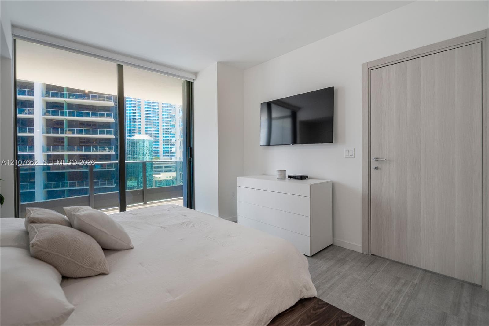 Floor-to-ceiling windows, wood-finish flooring, and light-toned interior doors