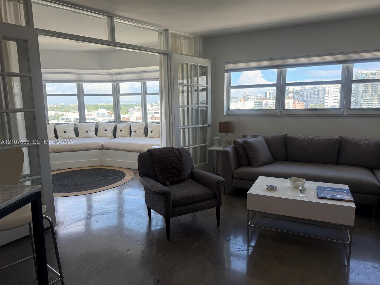 Polished concrete flooring, expansive wrap-around windows, built-in window seating, and glass-paned French doors