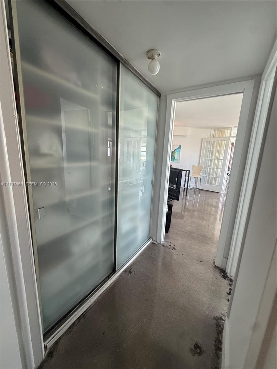 Sliding closet doors with frosted glass panels, polished concrete flooring, and flush-mount ceiling light fixture