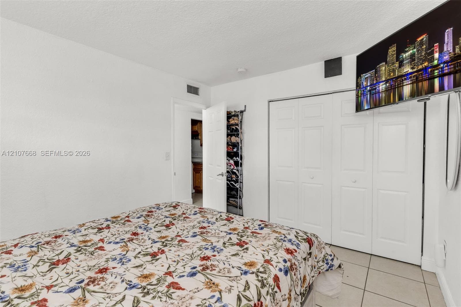 Room featuring white walls, tile flooring, and a multi-panel closet with white doors