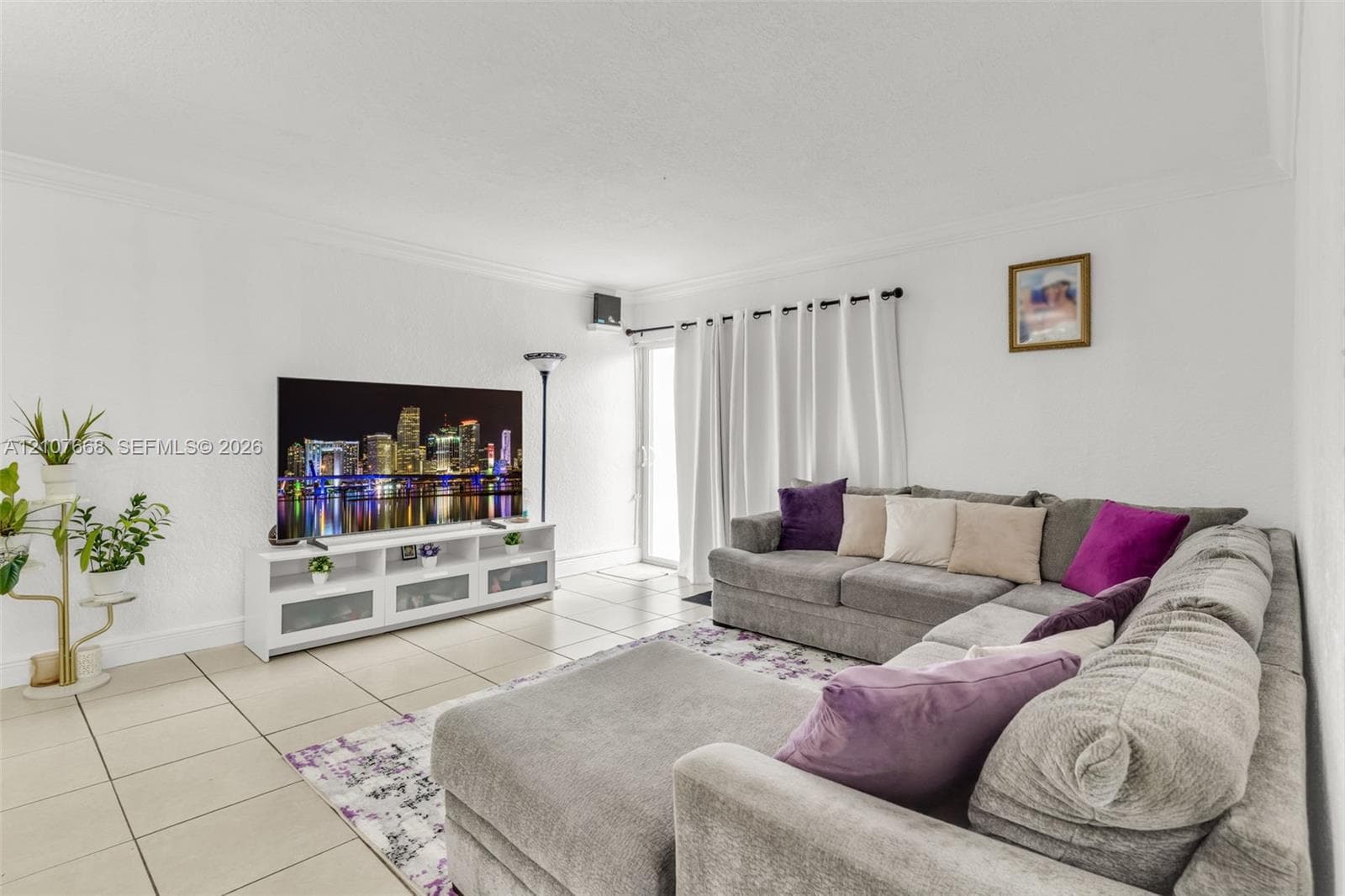 Living area featuring neutral tile flooring, crown molding, and a sliding glass door