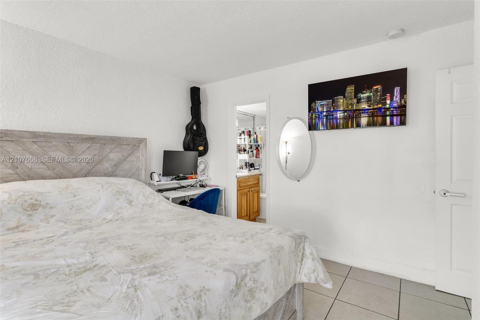 Neutral-toned tile flooring, white interior walls, and a six-panel door with a metallic lever handle