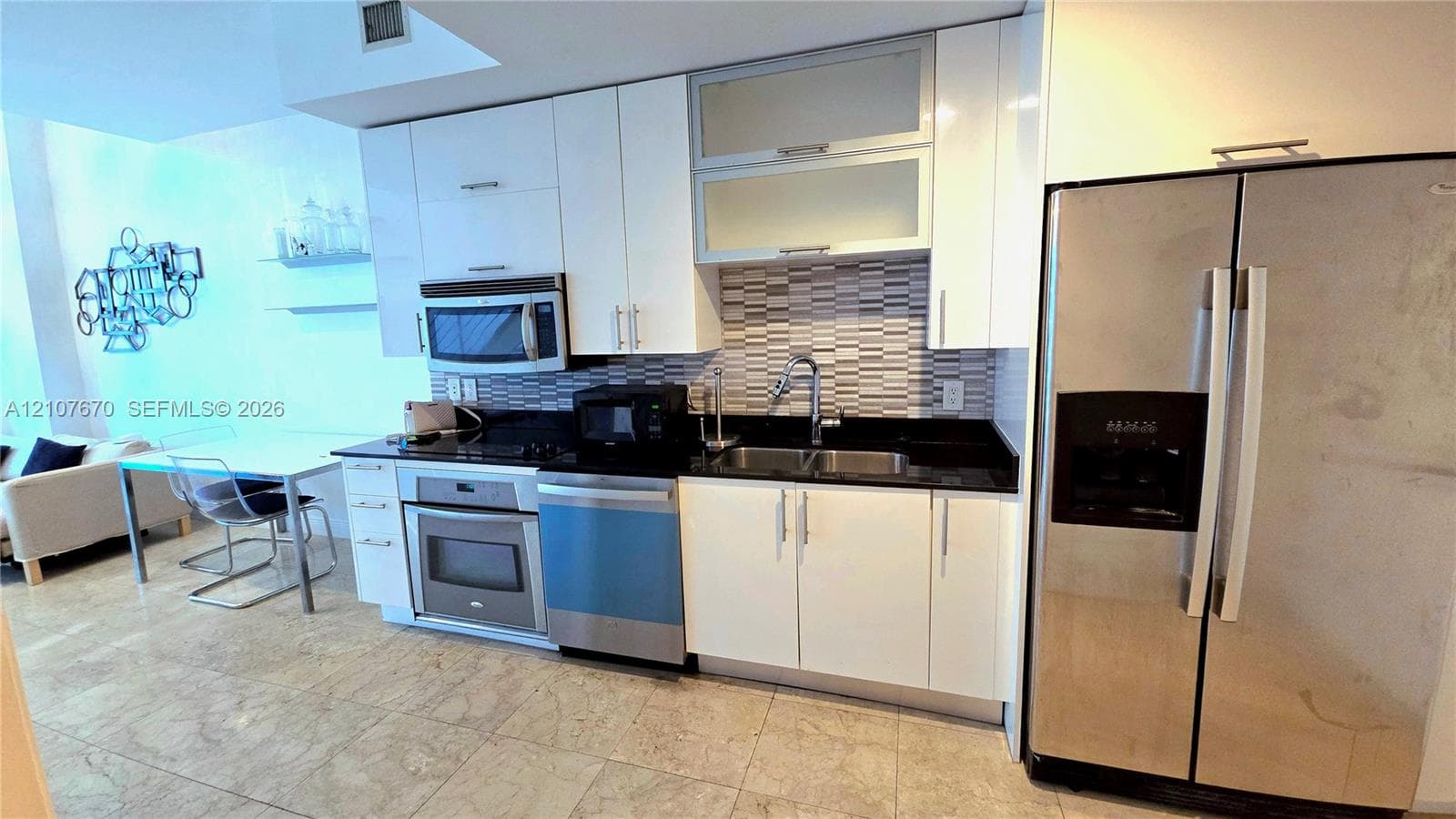 Kitchen featuring white cabinetry with glass-panel upper doors, dark stone countertops, stainless steel appliances, and a horizontal mosaic tile backsplash