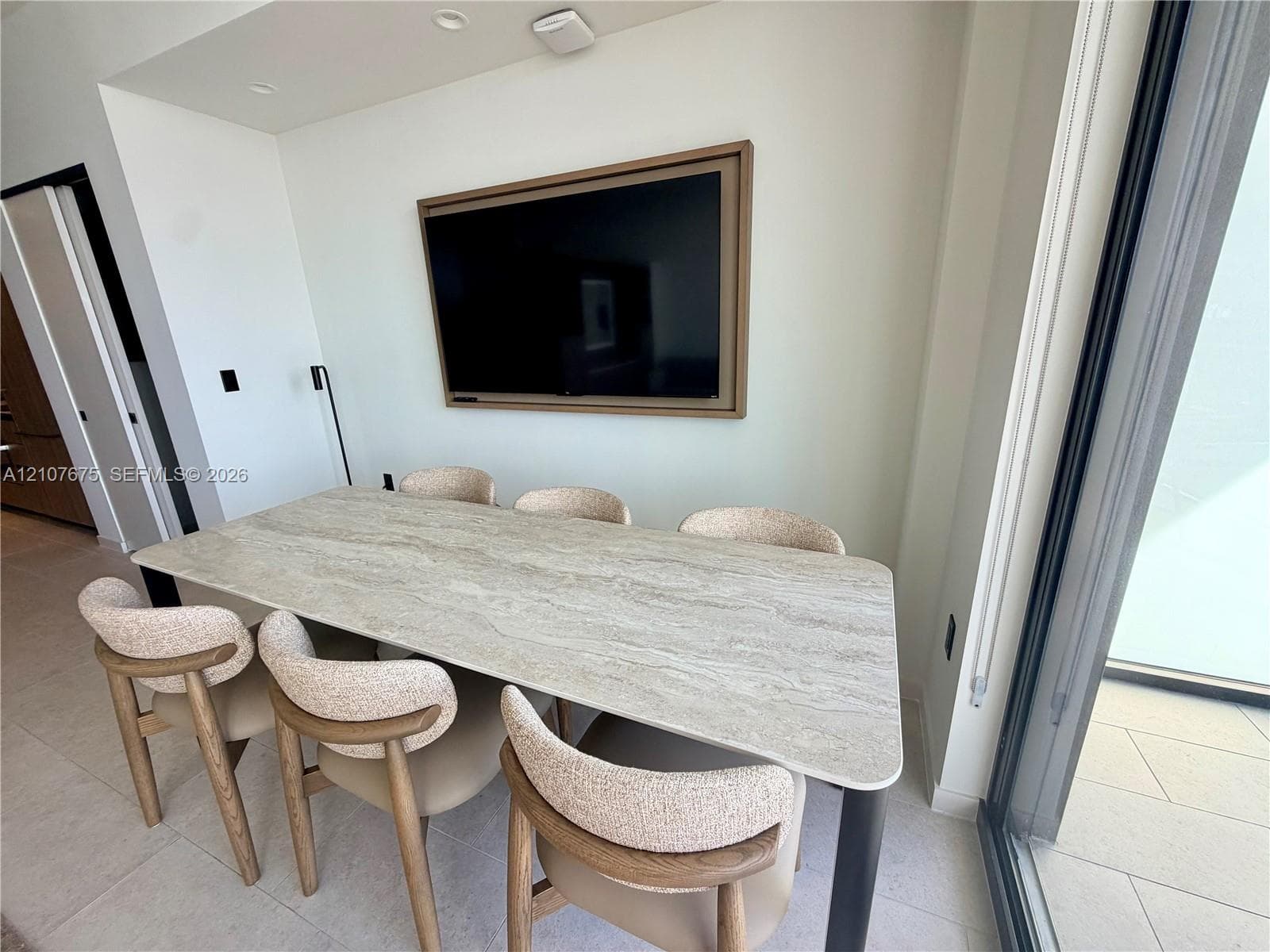 Recessed ceiling lighting, stone-top table with metal base, and expansive sliding glass door with external patio access