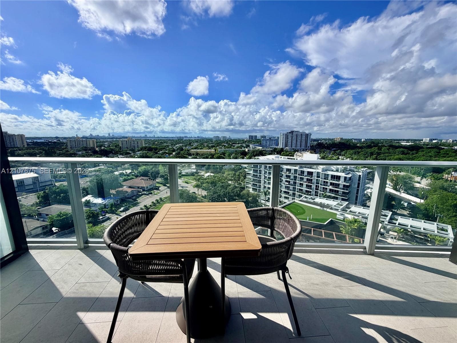 Private balcony featuring large-format tile flooring, a glass-panel railing, and panoramic urban horizon scenery
