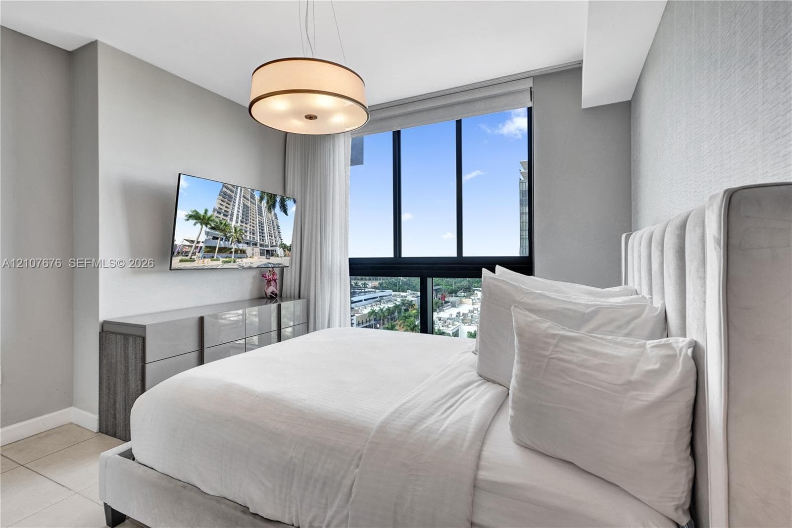 Floor-to-ceiling windows, drum pendant lighting, neutral textured wall covering, and large-format tile flooring