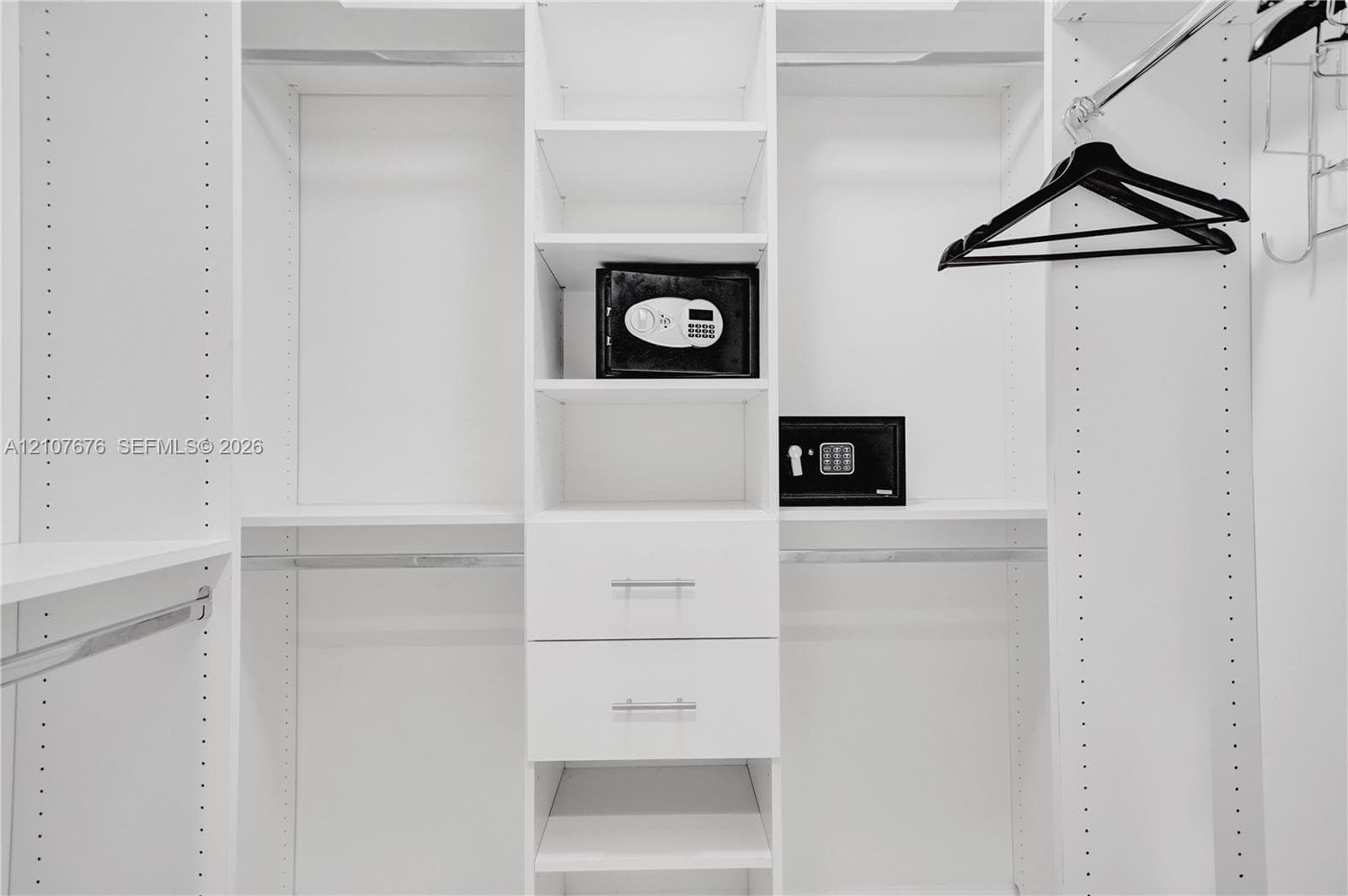 Custom walk-in closet featuring white laminate built-in cabinetry, adjustable shelving, dual soft-close drawers with silver-tone pulls, and integrated garment rods
