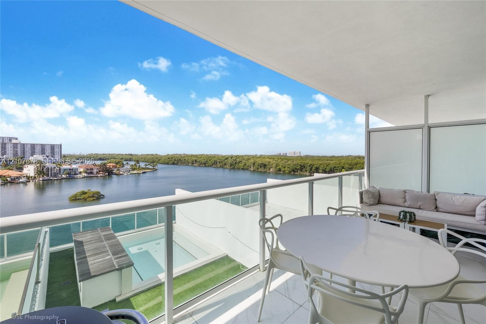 Covered terrace featuring glass panel railings, white tile flooring, and direct access to an outdoor pool with integrated wood decking